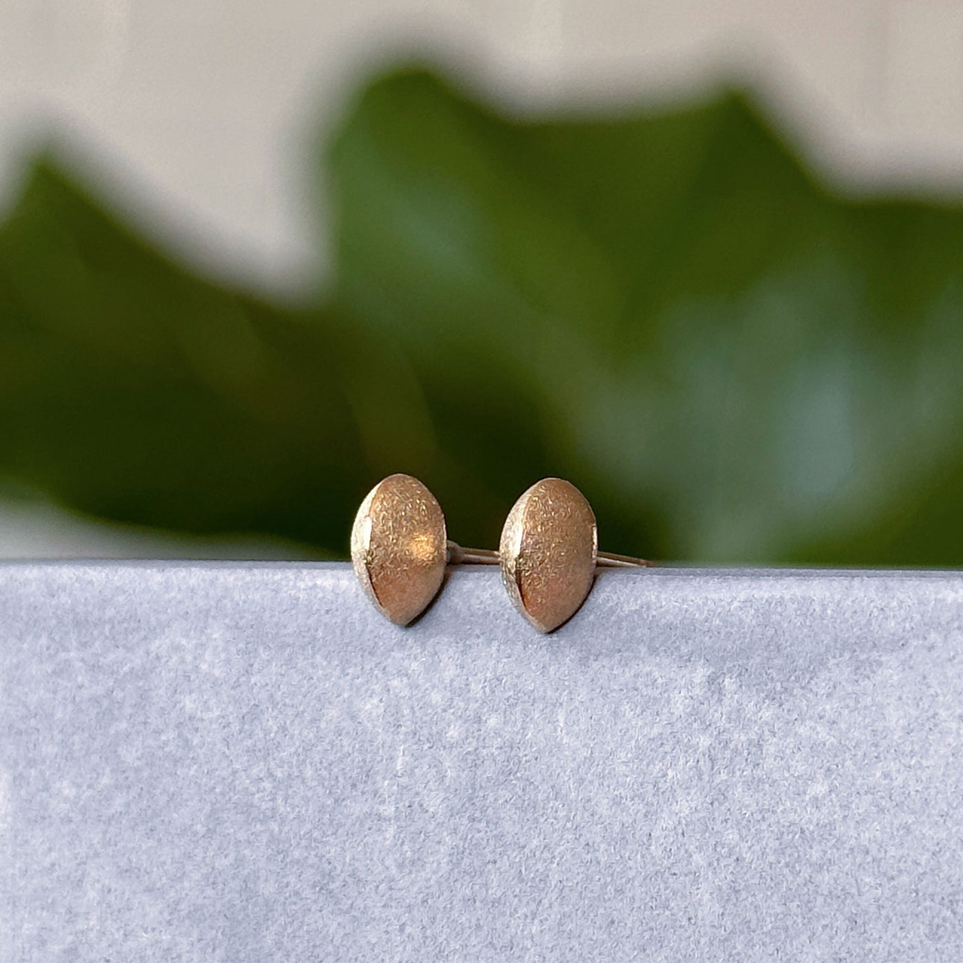 Yellow Gold Dewdrop Studs displayed on a concrete table, side angle