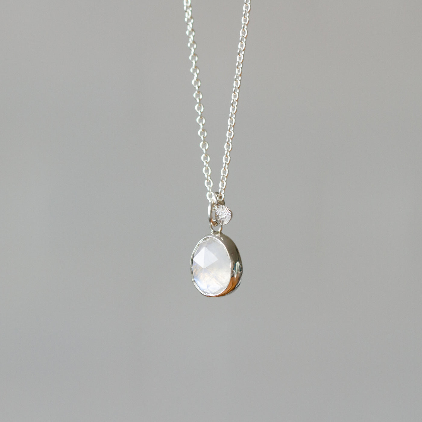 Rose Cut Moonstone Silver Theia Necklace #9 hanging in front of a white wall, side angle