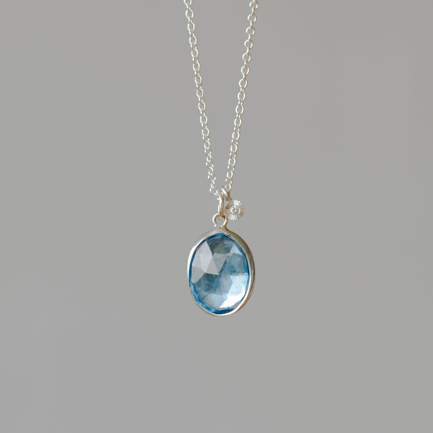 Rose Cut Swiss Blue Topaz Silver Theia Necklace #2 hanging in front of a wall, front angle