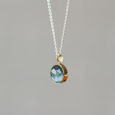 Rose Cut Moss Aquamarine Silver and Gold Theia Necklace #5 hanging in front of a wall, side angle