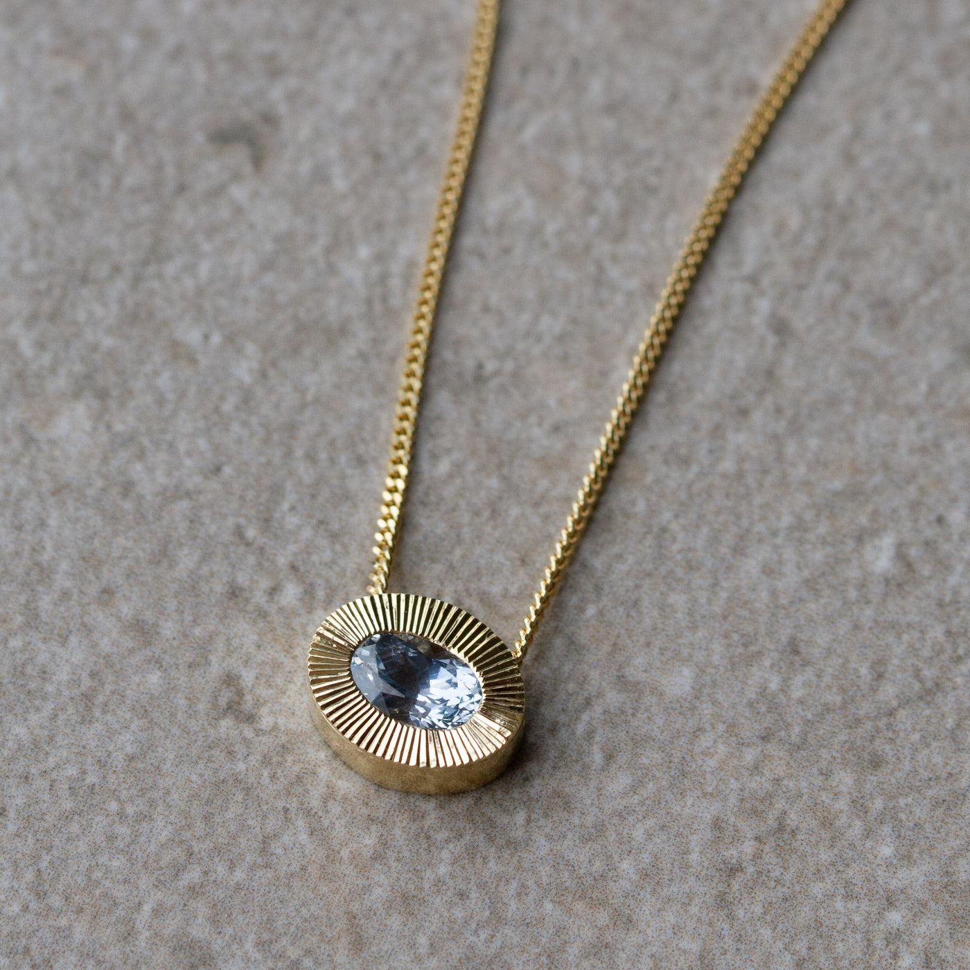 East-West Oval Aurora Necklace with Silver Montana Sapphire in Yellow Gold on a neutral background, side angle