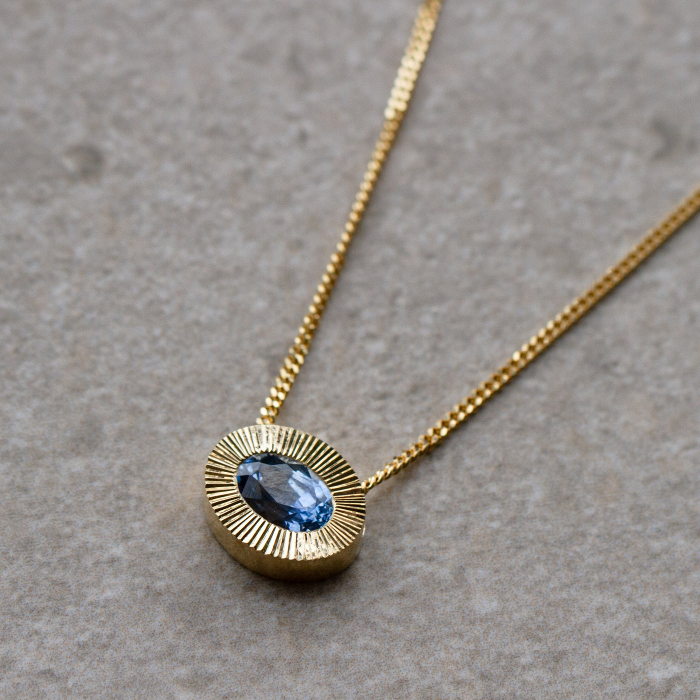 East-West Oval Aurora Necklace with Blue Montana Sapphire in Yellow Gold on a neutral background, side angle