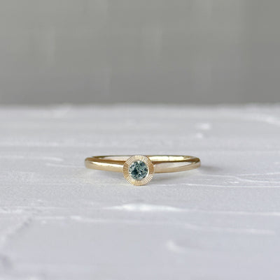 Teal Montana Sapphire Large Aurora Stacking Ring in Yellow Gold on a white table, front angle