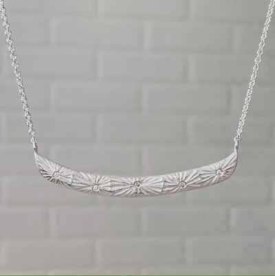 Sterling silver curved bar necklace with five scattered diamonds and an engraved sunburst pattern radiating from each | Corey Egan