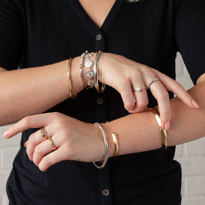 A model wears assorted silver and bronze bracelets including the silver thin denali bangle on the front wrist