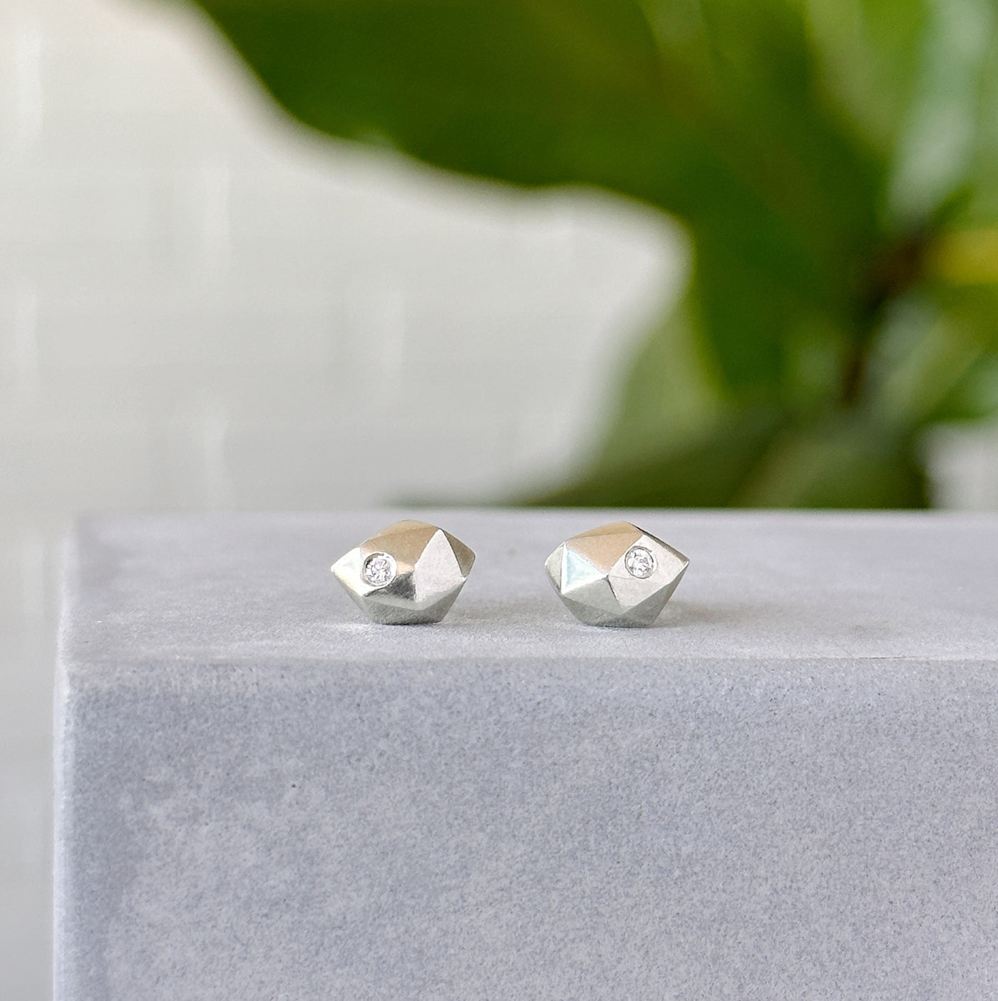 Tiny Fragment Diamond Stud Earrings sitting on concrete in front of a white wall, front angle