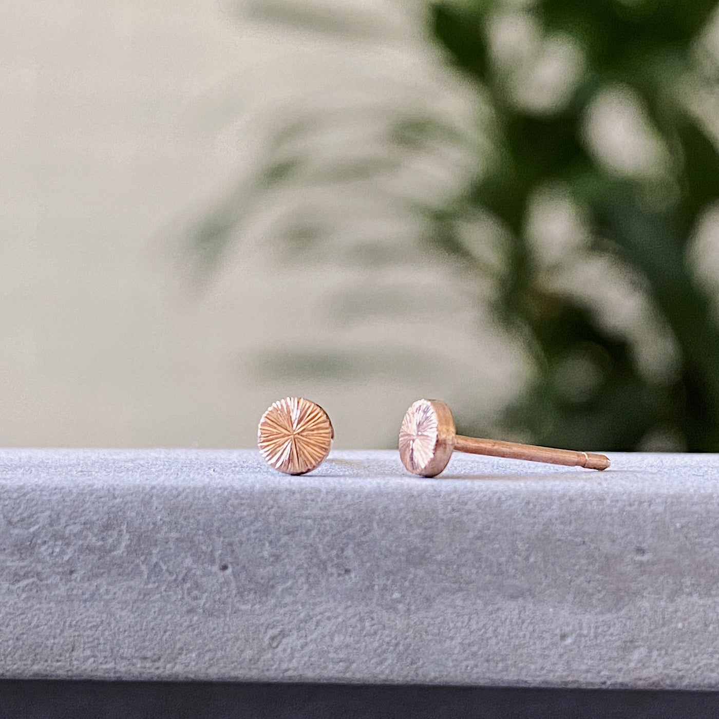 round rose gold stud earrings with sunburst engraving side view