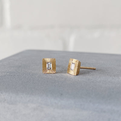 Side view of rectangle 14k yellow gold Aurora stud earrings with baguette diamond centers and engraved rays