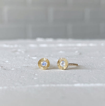 Small yellow gold Aurora engraved stud earrings with moonstone centers in natural light alternate view