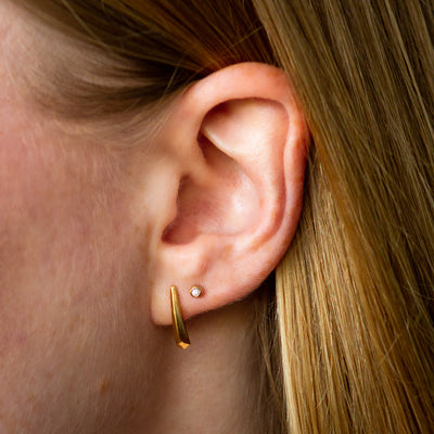 gold and diamond droplet studs with gold tapered fragment studs on an ear