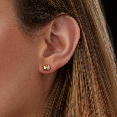 Geometric faceted gold wabi-sabi stud earrings with white diamonds in 14k yellow gold on an ear by Corey Egan