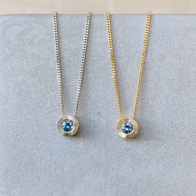 Small aurora necklace with a blue montana sapphire center white gold on left and yellow gold on the right