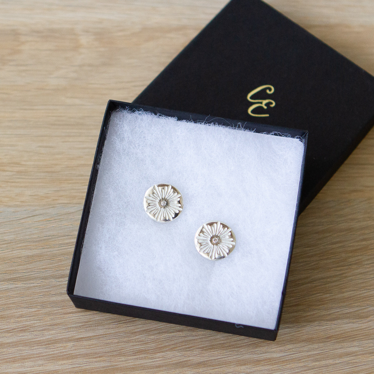 Sterling silver round cufflinks with a floral carved sunburst design and diamond centers in a gift box
