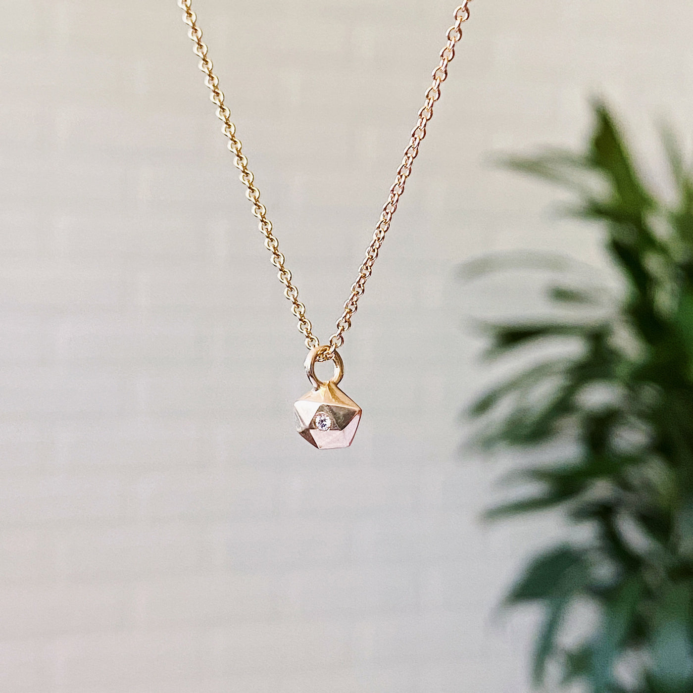 Faceted geometric gold tiny fragment necklace with a single white diamond in one facet side view in natural light | Corey Egan