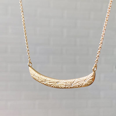 Side view of Curved bar necklace with five scattered diamonds and carved sunburst motif by Corey Egan