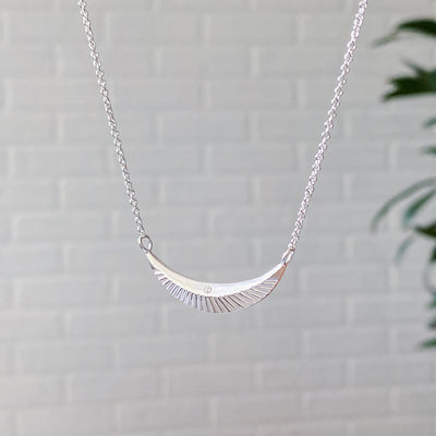 Side view of Crescent necklace with carved rays and a single diamond in sterling silver 