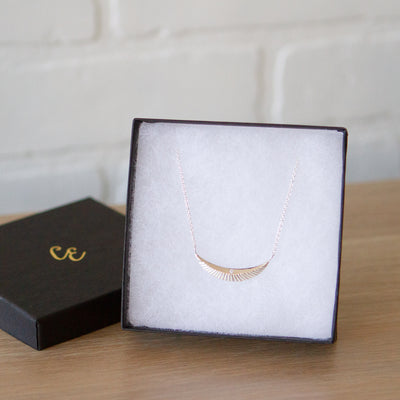 Crescent necklace with carved rays and a single diamond in sterling silver in a gift box