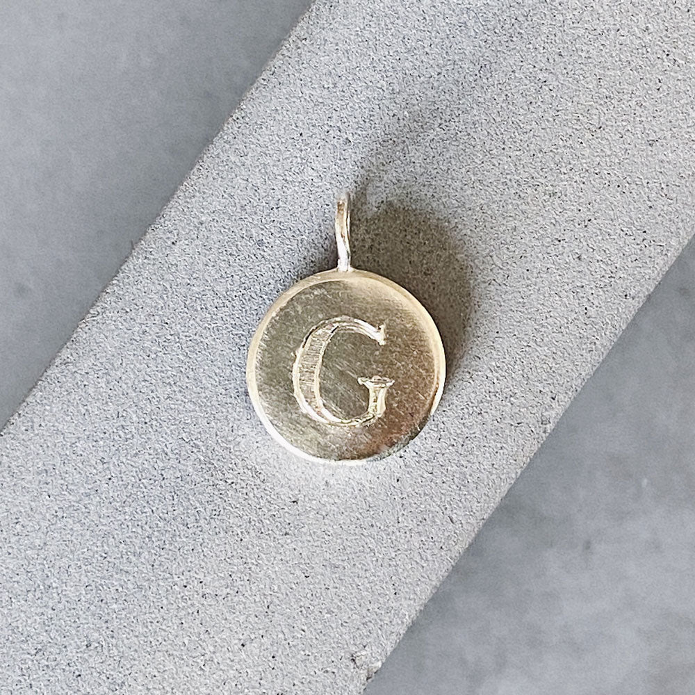Sterling silver round pendant with an engraved block letter G