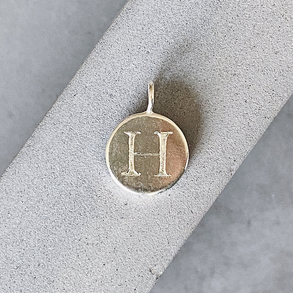 Sterling silver round pendant with an engraved block letter H