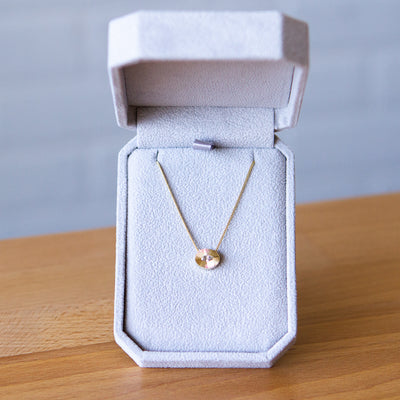 Antique step-cut diamond in a yellow gold oval aurora pendant with engraved rays in a gift box