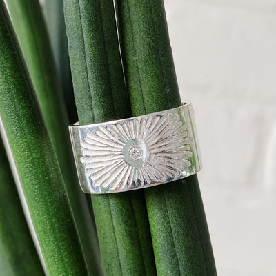 Sterlign silver wide band with single diamond and a carved sunburst design in natural light by Corey Egan