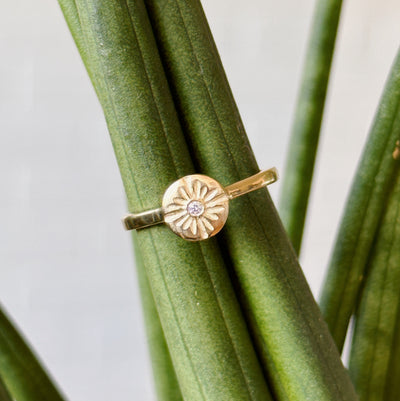 Lucia Small Yellow Gold and Diamond Ring displayed on a plant, tilted slightly sideways 