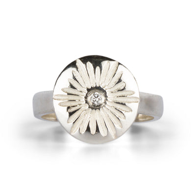 Large carved sunburst ring with a diamond center in sterling silver on a white background by Corey Egan