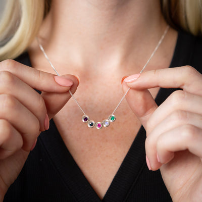 A model wears one necklace containing five small aurora pendants with the following gemstones: amethyst, blue sapphire, ruby, moonstone, and emerald