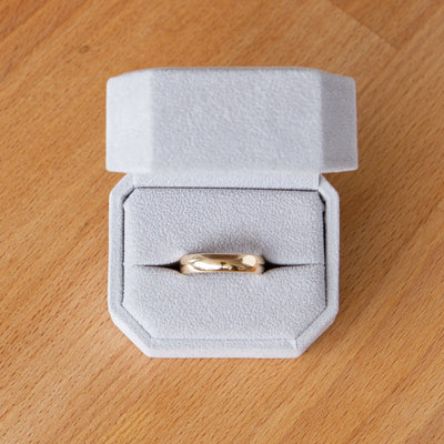 Shiny half round wide Muir wedding band in 14k yellow gold in a ring box