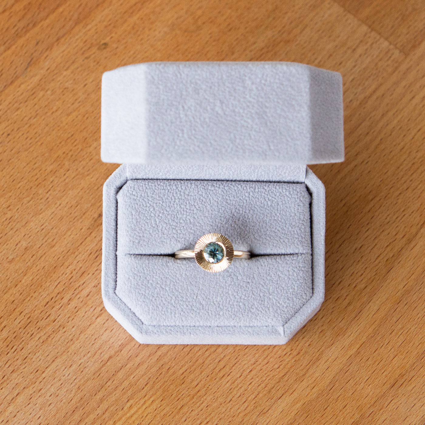 Round mint green Montana sapphire in a 14k yellow gold Aurora ring with an engraved halo border in a gift box