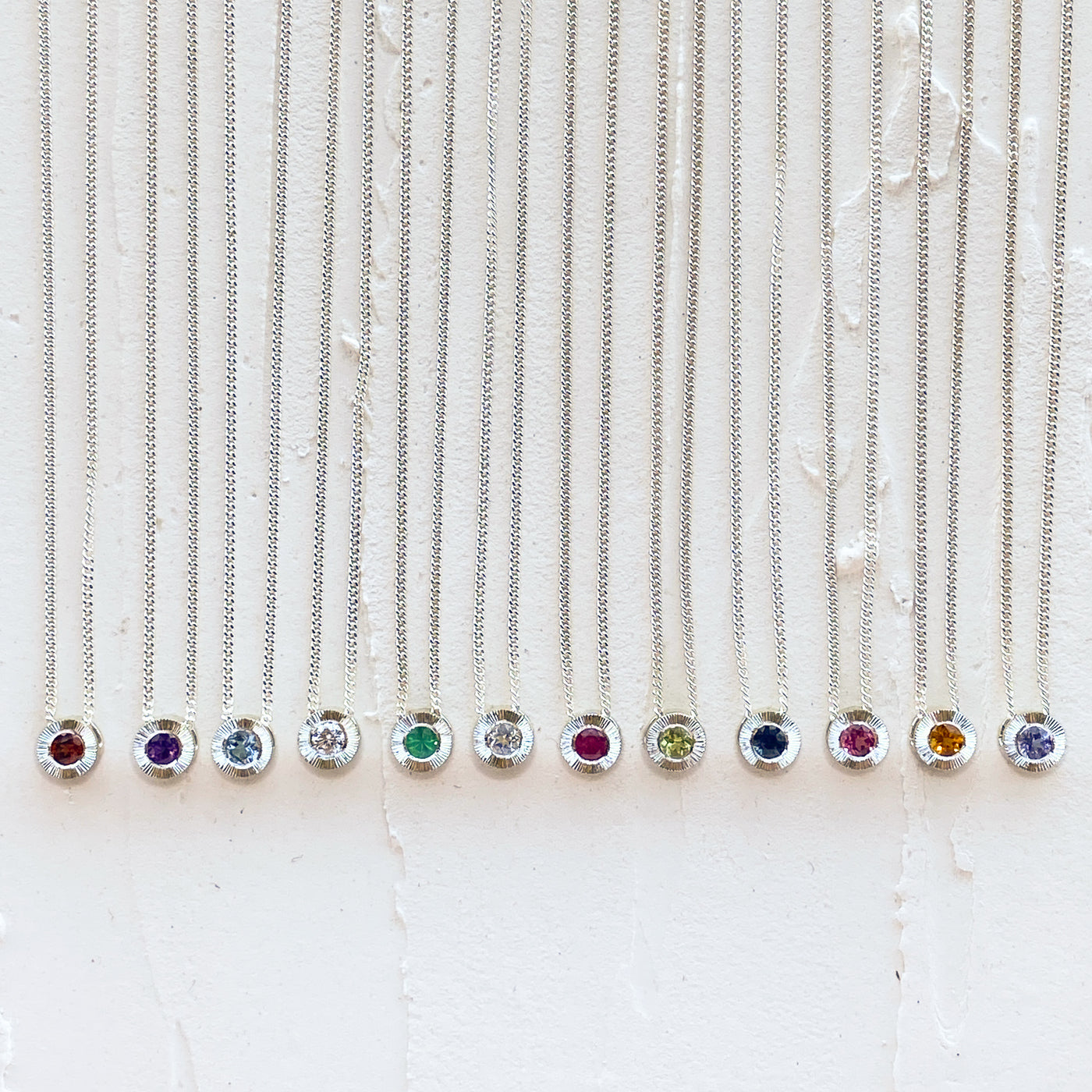 Sterling silver aurora necklaces with birthstones garnet for January,  amethyst for February, aquamarine for March, diamond for April, emerald for May, moonstone for June, ruby for July, peridot for August, blue sapphire for September, pink tourmaline for October, citrine for November, and tanzanite for December