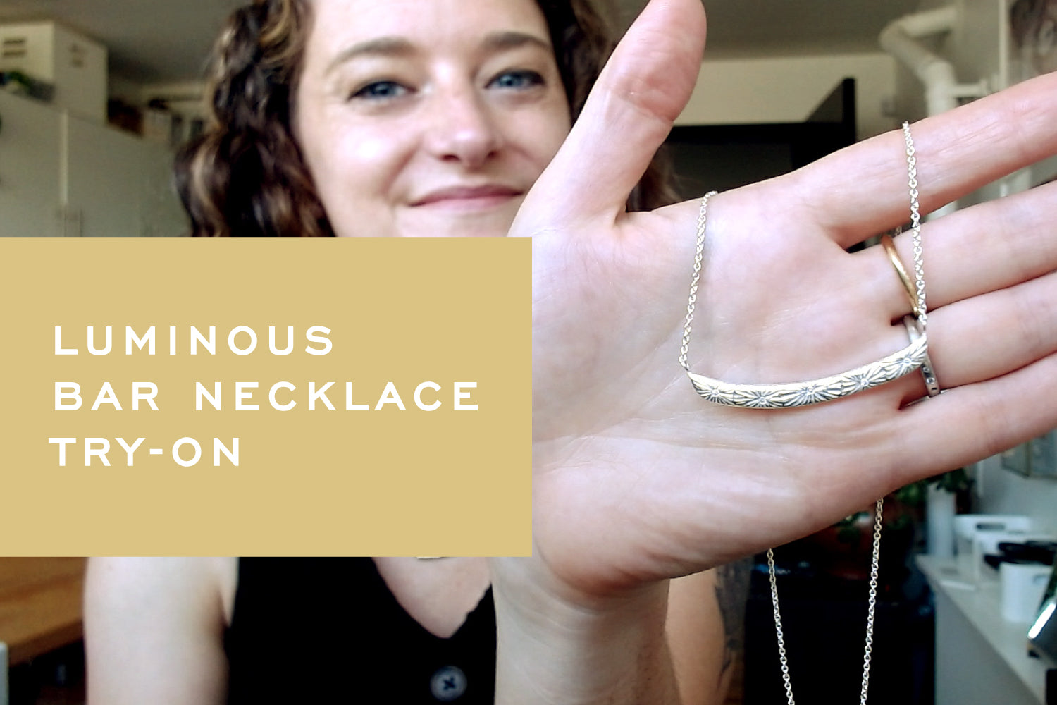 Corey holds up the Luminous Bar Necklace in silver