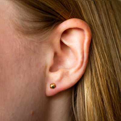 Micro Fragment small faceted stud earrings in gold vermeil by Corey Egan on an ear
