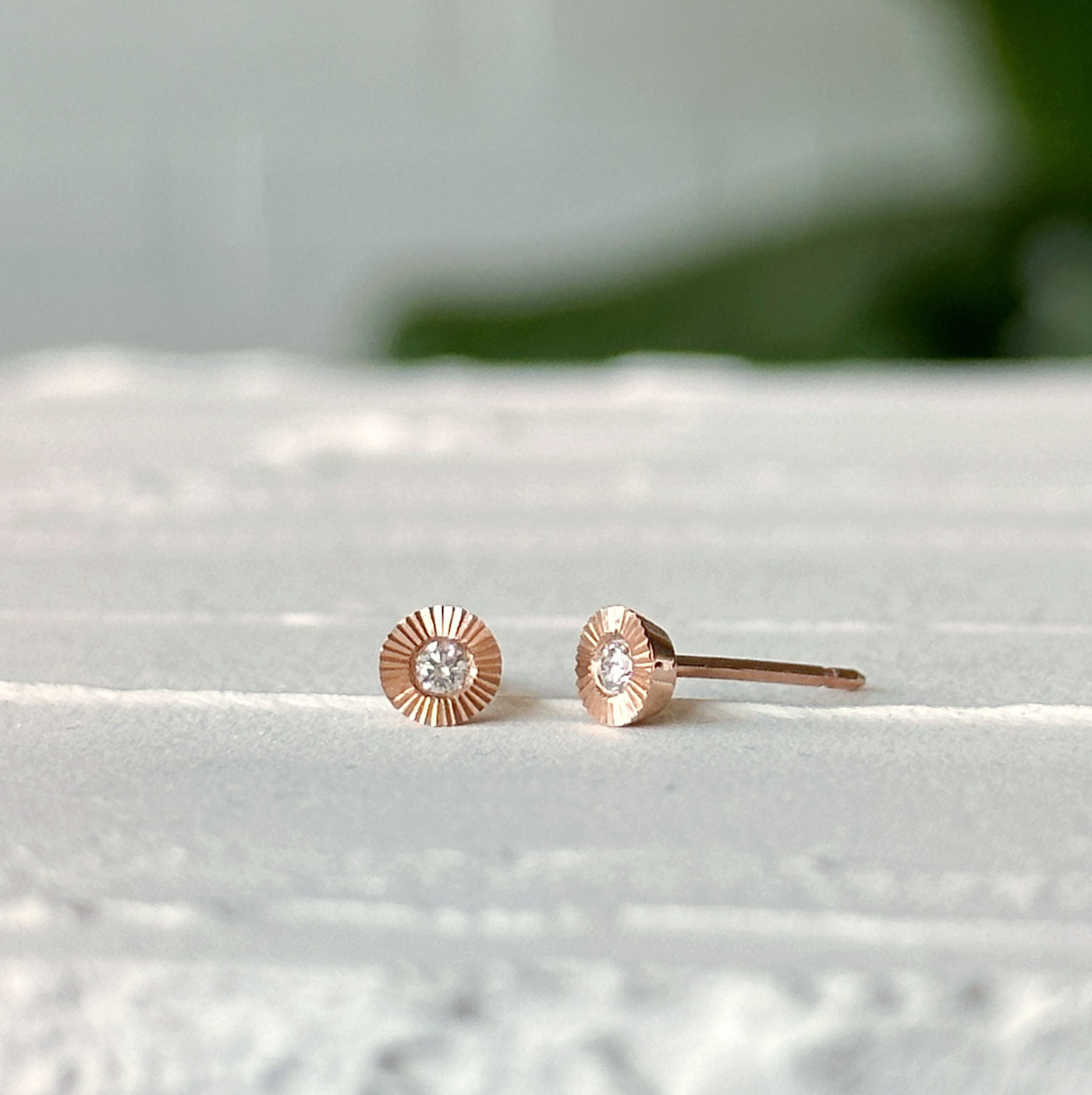 Small Aurora Diamond Stud Earring in Rose Gold sitting on a white table, side view