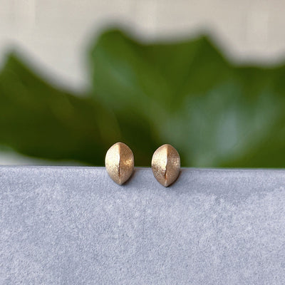 Yellow Gold Dewdrop Studs displayed on a concrete table, front angle