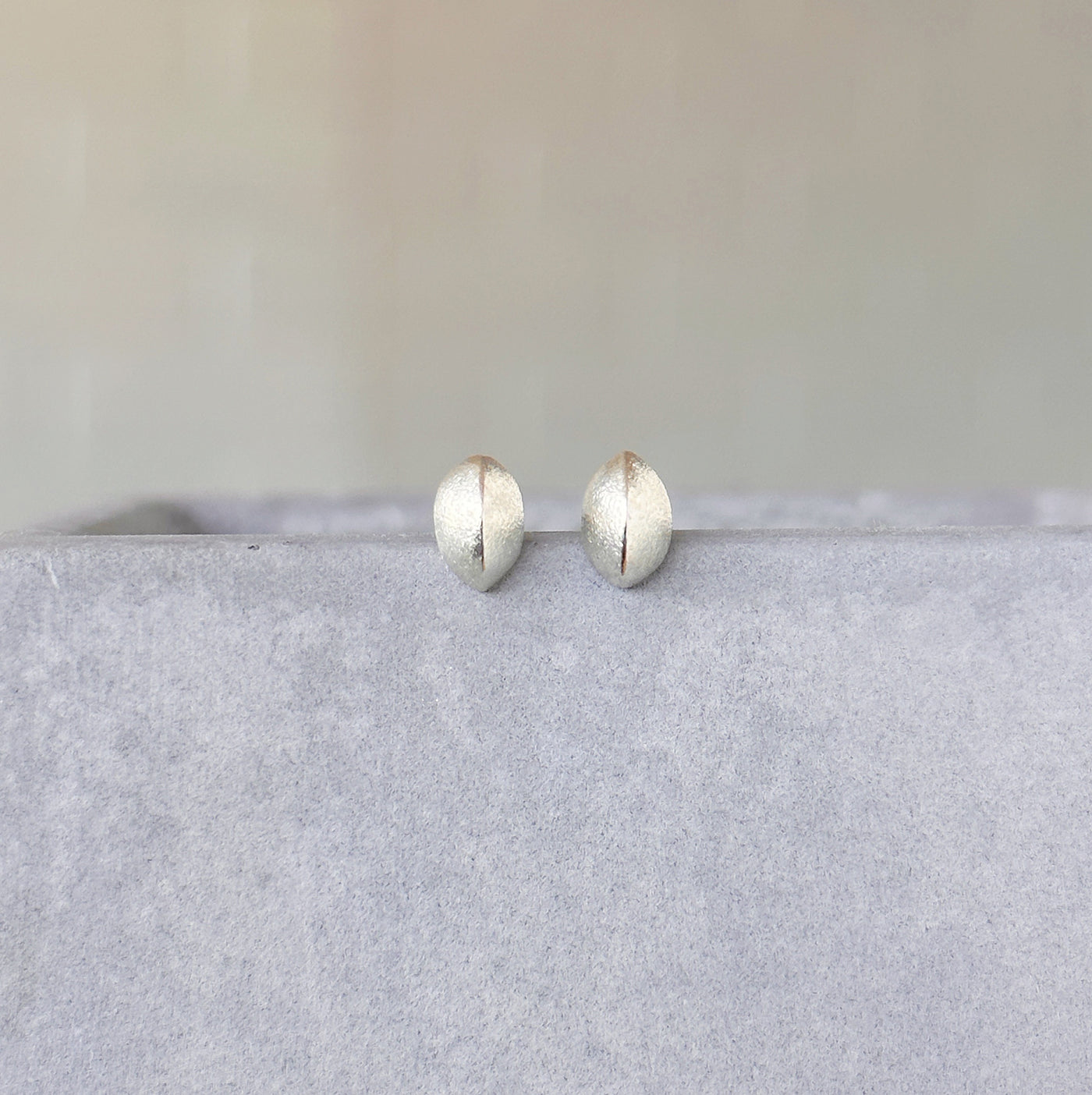 Silver Dewdrop Studs on a concrete table in front of a white wall, front angle