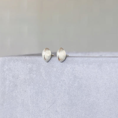 Silver Dewdrop Studs on a concrete table in front of a white wall, side angle