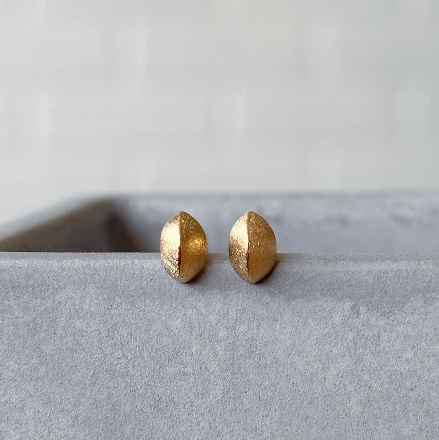 Vermeil Dewdrop Studs displayed on a concrete table, front angle