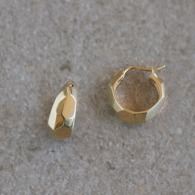 Gold Fragment Huggie Hoops on a natural background, side angle
