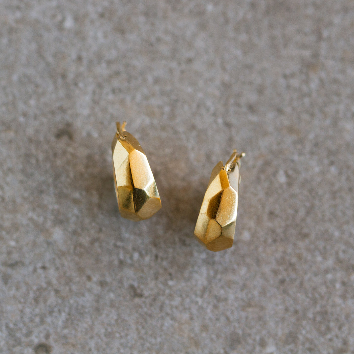 Vermeil Fragment Huggie Hoops on a natural background, front angle