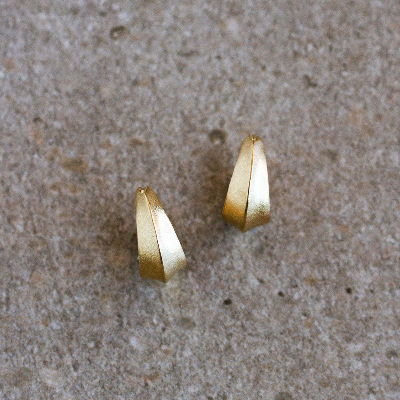 Gold Morph Huggie Hoops on a natural background, front angle