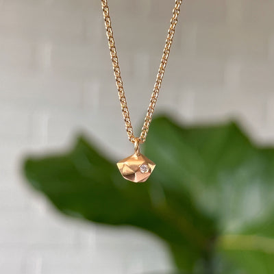Vermeil Tiny Fragment Diamond Necklace hanging in front of a white brick wall, front angle