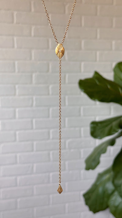 Vermeil Prism Lariat hanging in front of a white wall
