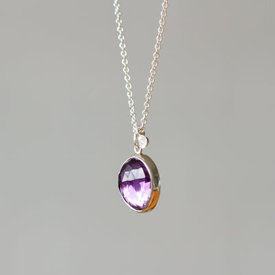 Rose Cut Amethyst Silver Theia Necklace #4 hanging in front of a white wall, side angle