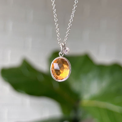 Citrine Theia Necklace in Sterling Silver hanging in front of a white wall, front angle