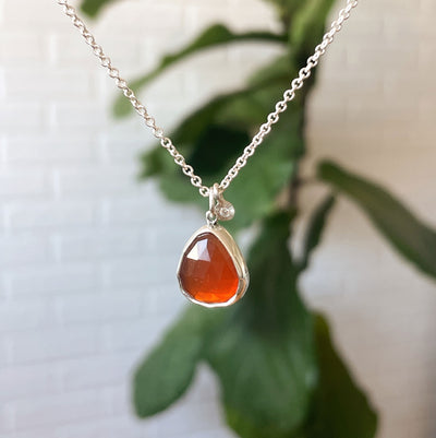 Fire Opal Theia Necklace in Sterling Silver hanging in front of white wall, side angle