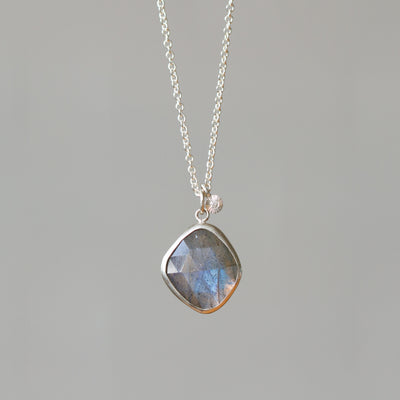 Rose Cut Labradorite Silver Theia Necklace #12 hanging in front of a white wall, front angle