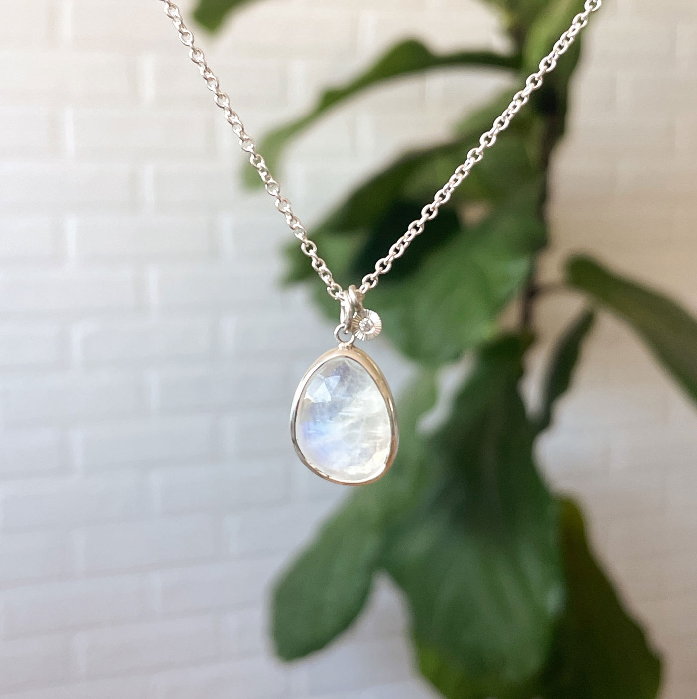 Moonstone Theia Necklace in Sterling Silver hanging in front of a white wall, front angle