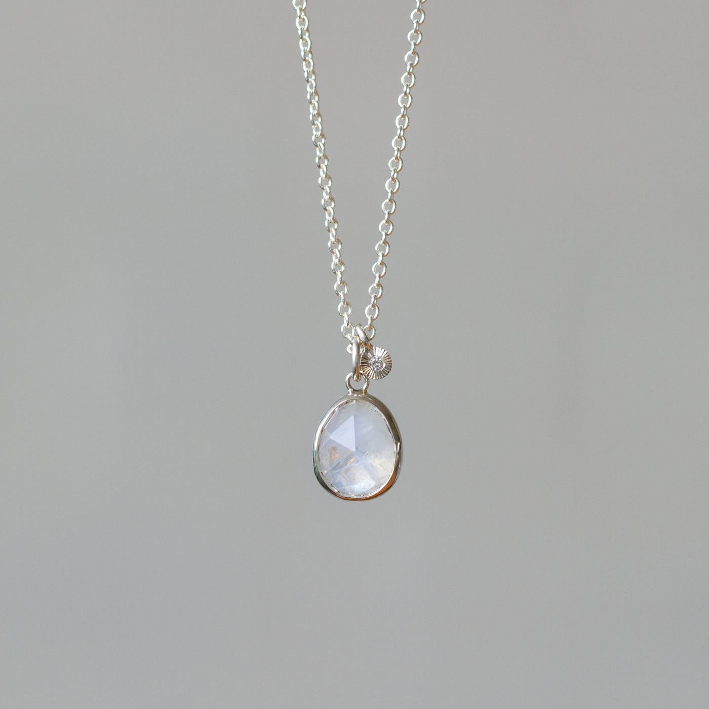 Rose Cut Moonstone Silver Theia Necklace #9 hanging in front of a white wall, front angle
