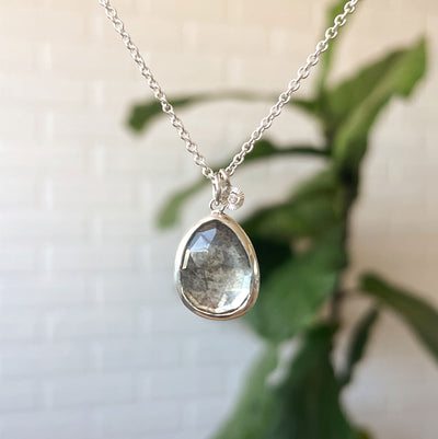 Moss Aquamarine Theia Necklace in Sterling Silver #8 hanging in front of a white wall, front angle